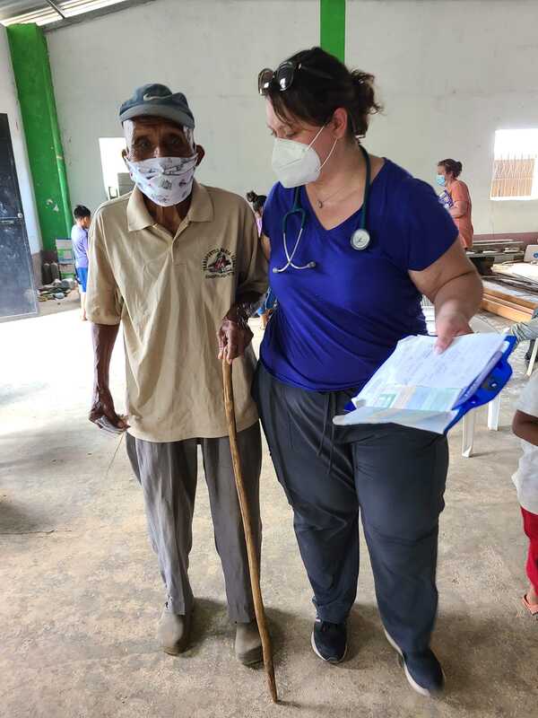A volunteer helping a man with a walking cane.